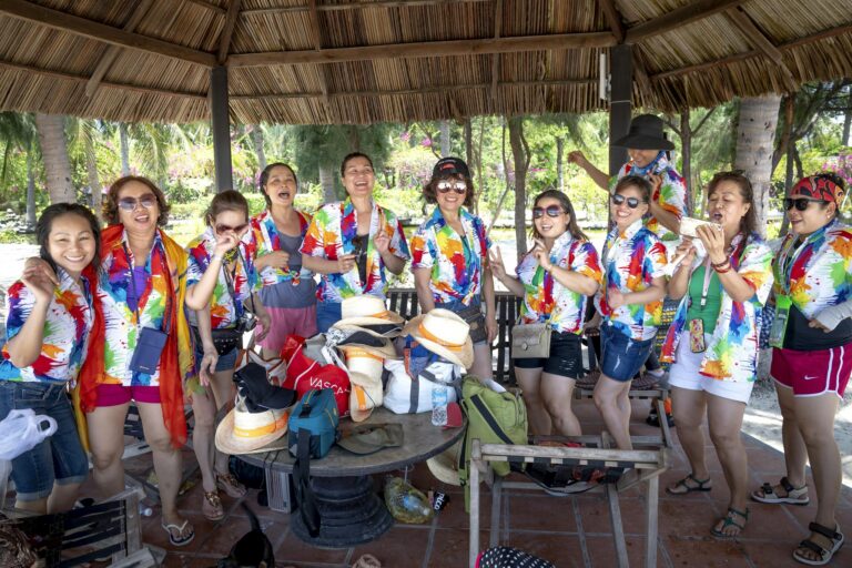 A joyful group of Asian women celebrating outdoors in vibrant shirts under a gazebo.
