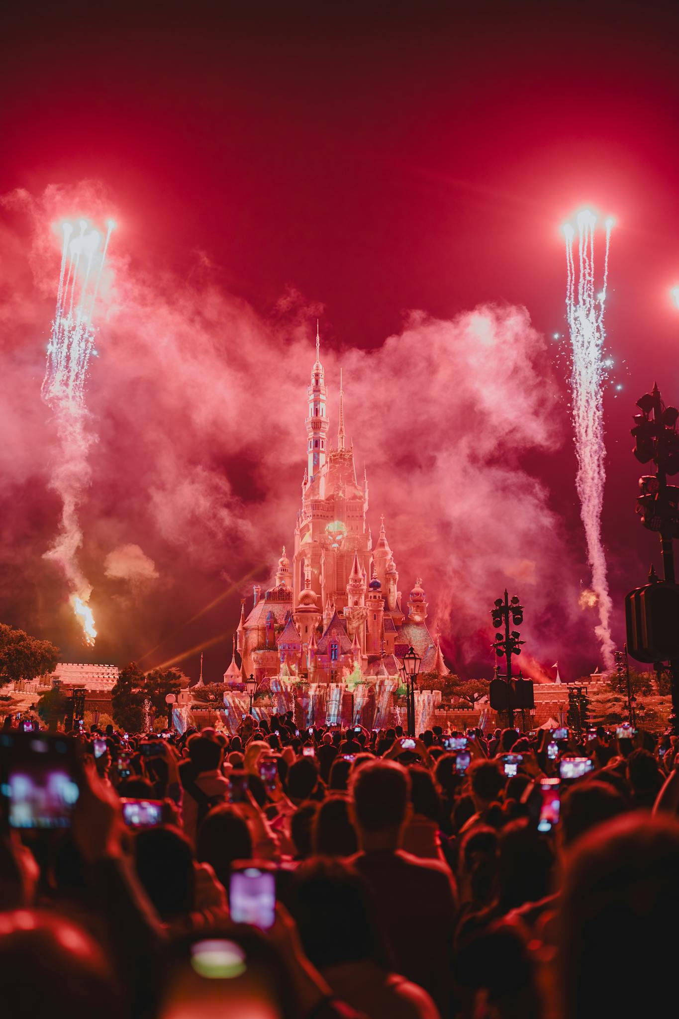Crowd enjoys a vibrant fireworks display over Hong Kong Disneyland Castle at night. Perfect for festive celebrations.